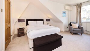 Une chambre à coucher avec un lit, des tables de chevet, une chaise et une fenêtre.