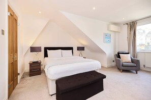 Une chambre à coucher avec un lit, des tables de chevet, une chaise et une fenêtre.