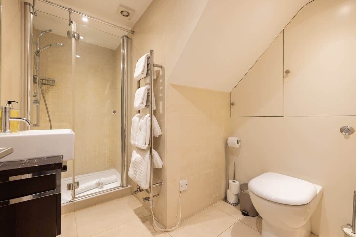 A bathroom with a glass-enclosed shower, a toilet, and a sink.