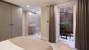 A bedroom with a bed, a wardrobe, a sliding door to a balcony, and a brick wall.