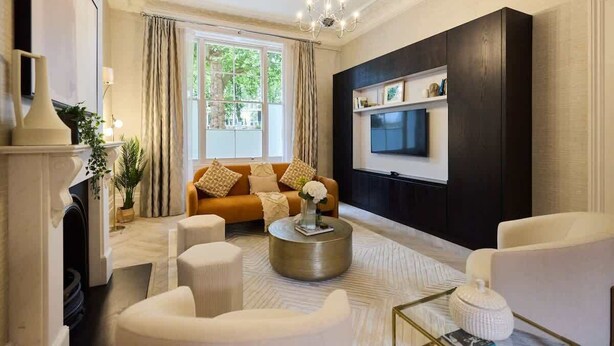 A living room with a sofa, coffee table, and TV mounted on a dark wall.