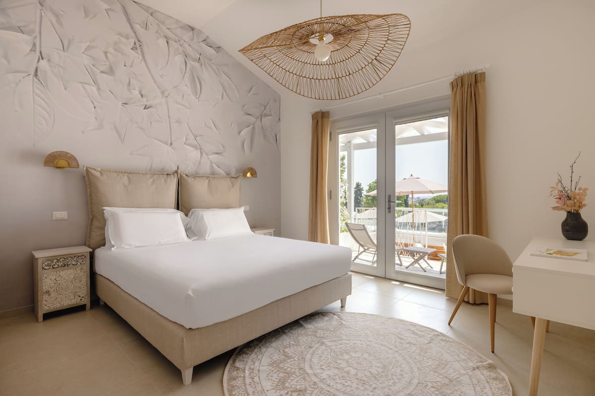 A modern bedroom with a large bed, a round rug, a desk, and a chair.