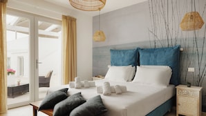 A modern bedroom with a large bed, a wooden bench, and a nightstand with a lamp. - Nu Aria Taunus Relais  (Numana)