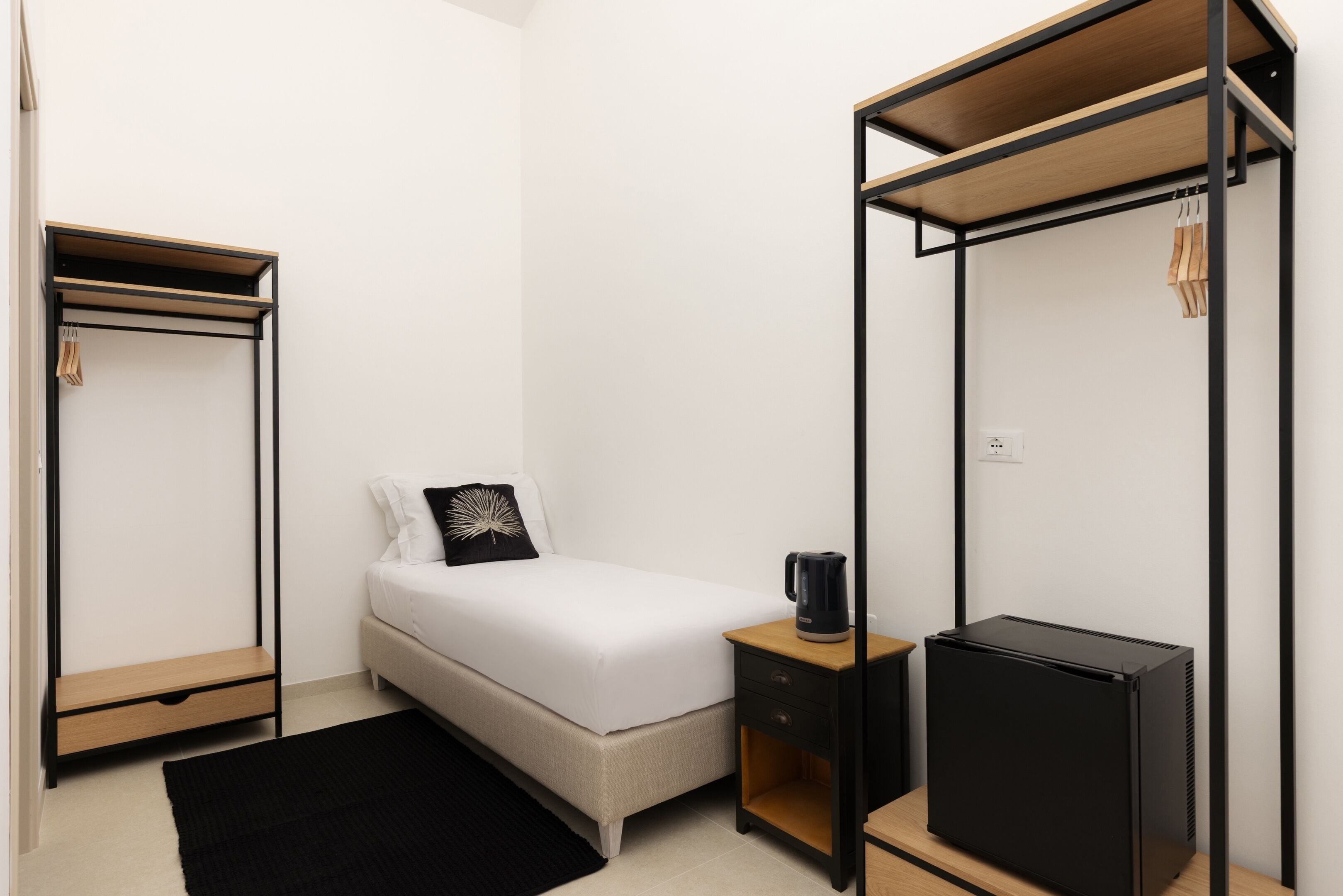 Un dormitori modern i minimalista amb un llit, una tauleta de nit, un armari i un calefactor.