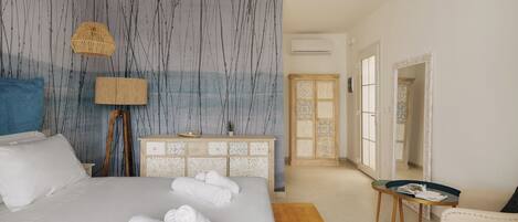 A bedroom with a bed, a dresser, a chair, and a small table.