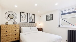 Une chambre à coucher avec un lit, une commode et des œuvres d’art murales.