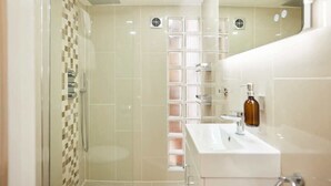 Une salle de bain moderne avec une douche à parois de verre, un lavabo blanc et un miroir.