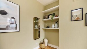 A hallway with a mirror, shelves with decorative items, a vase, and a framed picture. - The Waterlow Park Wonder - 2BDR with Study (Greater London)