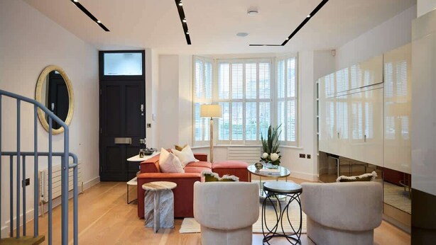 Una sala de estar moderna con un sofá, dos sillones, una mesa de centro, una lámpara y un amplio ventanal.