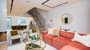 Una sala de estar moderna con una escalera, un espejo redondo y un sofá rojo.