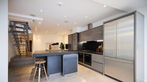 Una cocina moderna con una isla central, electrodomésticos de acero inoxidable y una escalera en espiral.
