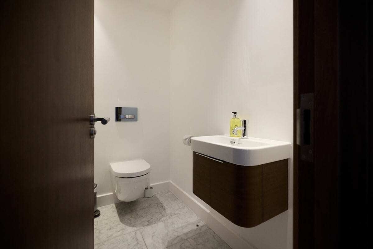 A small bathroom with a toilet, a sink, and a soap dispenser.