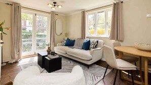 Een woonkamer met een bank, een salontafel, een eettafel en uitzicht op buiten.