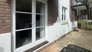 Een gebouw met een witte gevel, een bakstenen gedeelte en een balkon met een metalen hekwerk.