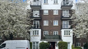 Een meerlaags woongebouw met balkons, een hoofdingang en een bord met informatie over beschikbare kamers.