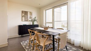 A dining area with a table, chairs, a cabinet, and a window with curtains.