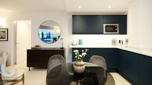 A modern kitchen with dark cabinets, a microwave, and a round mirror above the dining table. - The Melbray Escape - Trendy 2BDR Apartment (Greater London)