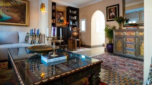 Un salon spacieux avec une table basse en verre, un canapé, une bibliothèque et un meuble décoratif.