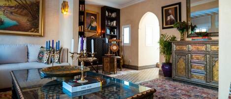 A spacious living room with a glass coffee table, a sofa, a bookshelf, and a decorative cabinet.