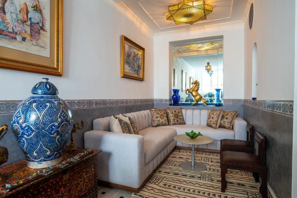 Un salon comprenant un canapé, une table basse et des objets décoratifs, notamment un vase bleu et une statuette de cheval dorée.