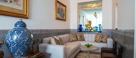 Un salon comprenant un canapé, une table basse et des objets décoratifs, notamment un vase bleu et une statuette de cheval dorée.