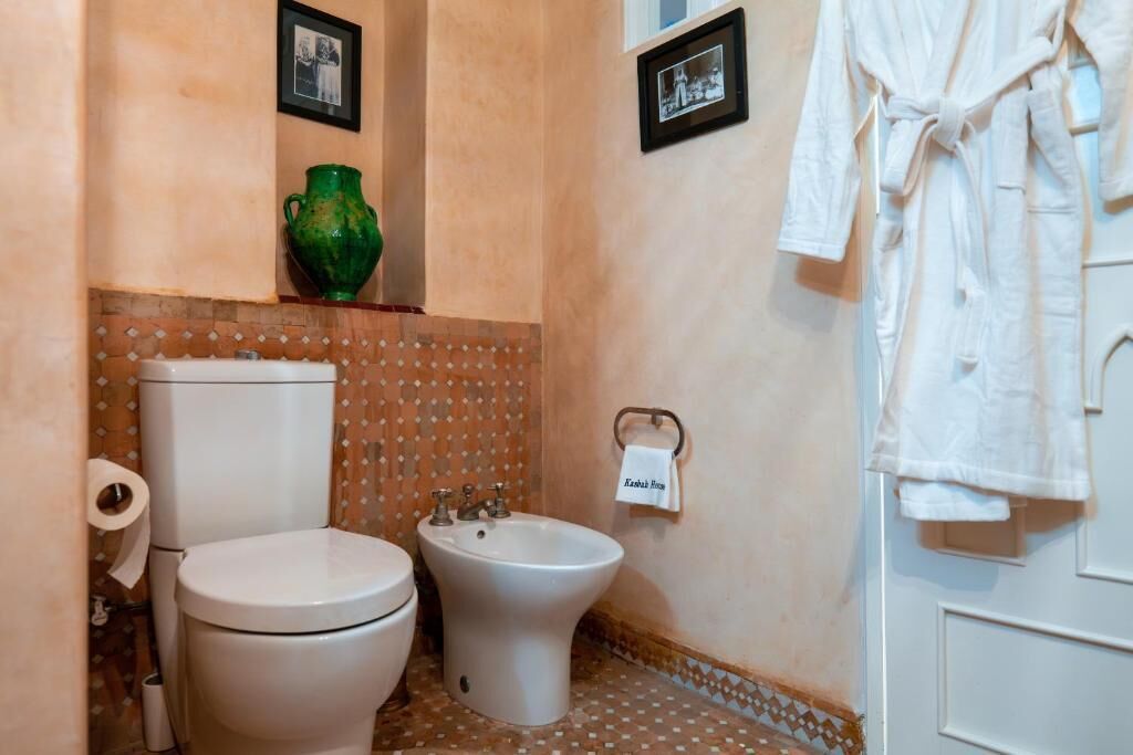 Un baño con inodoro, bidé y toallero con una toalla colgada.