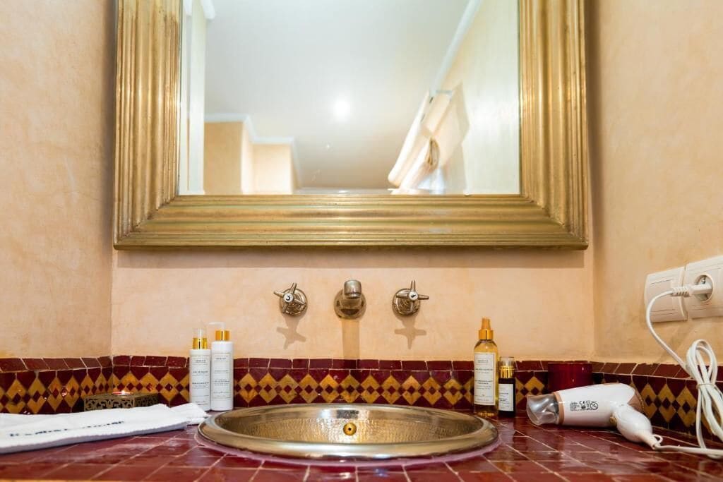 A bathroom with a sink, mirror, and toiletries.