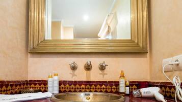A bathroom with a sink, mirror, and toiletries.