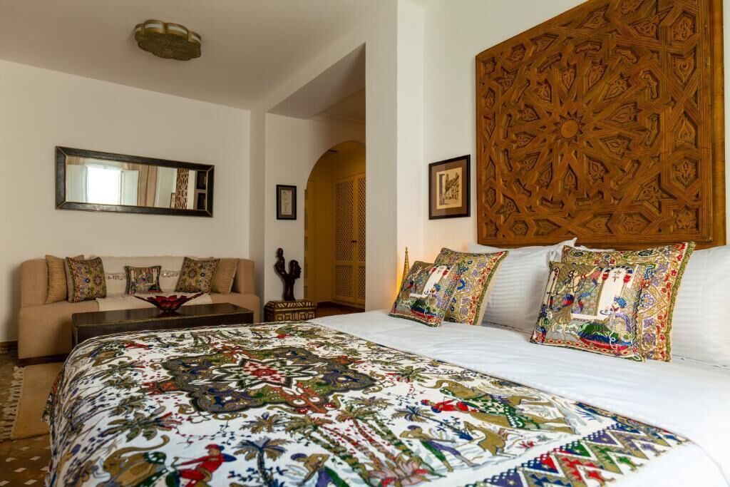 A bedroom with a large bed, a sofa, and a decorative headboard.