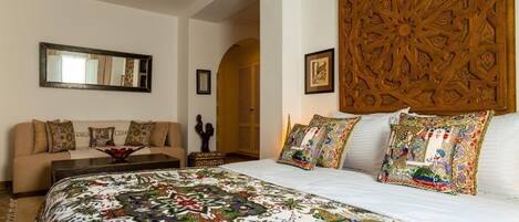A bedroom with a large bed, a sofa, and a decorative headboard.