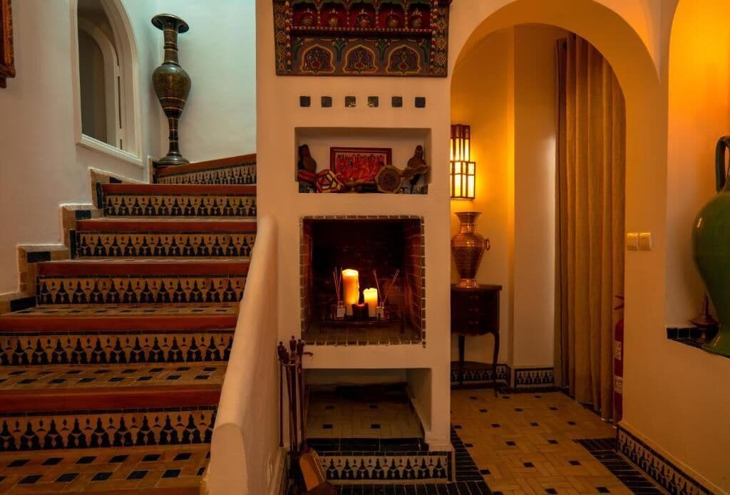 A staircase with intricate tile patterns leading to a fireplace with candles.
