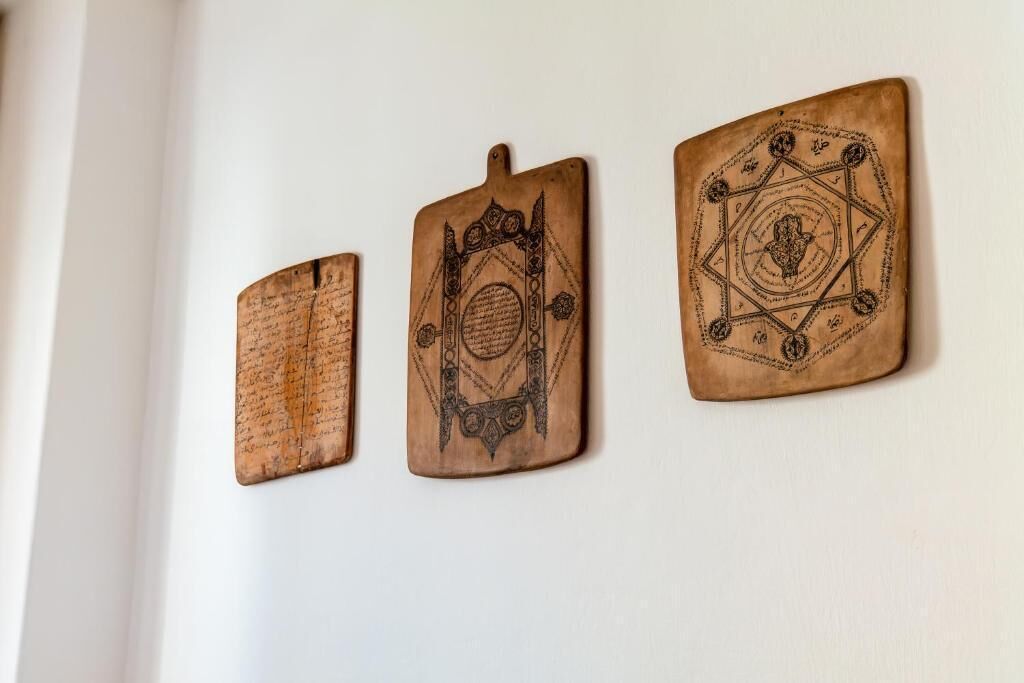Three wooden plaques with intricate designs and text on a wall.