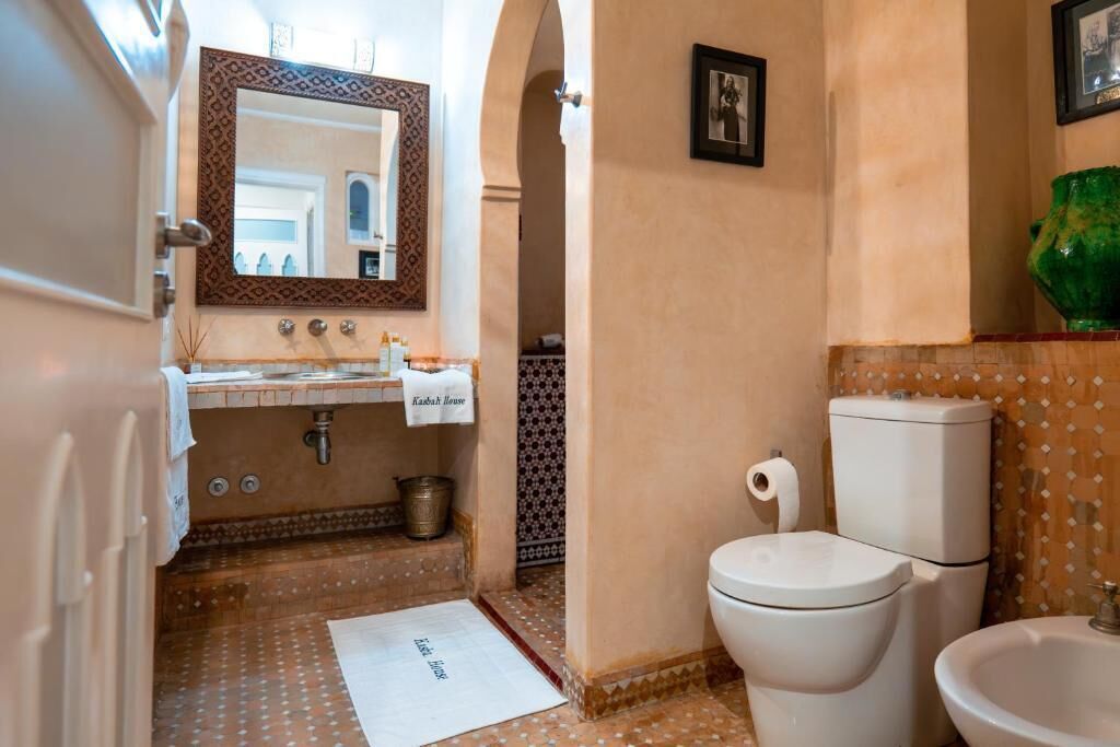 A bathroom with a sink, mirror, toilet, and bidet.