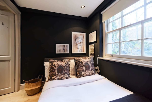 Une chambre à coucher avec un lit, une fenêtre et des œuvres d’art accrochées au mur.