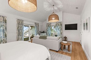 Une chambre à coucher avec un lit, un canapé, une télévision et une fenêtre avec des rideaux.