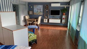 A modern bedroom with a bed, a desk, a chair, a small table, and a TV. - Ilonas Home (Baden-Baden)