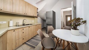 Eine moderne Küche mit Holzschränken, einem Edelstahlkühlschrank und einem Essbereich mit weißem Tisch und Stühlen.