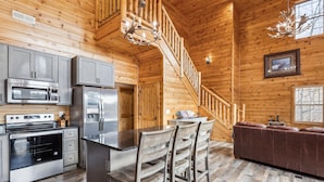 A wooden cabin interior with a kitchen, dining area, and a staircase. - Wild Heart Lodge 4 Bedroom Cabin (Sevierville)