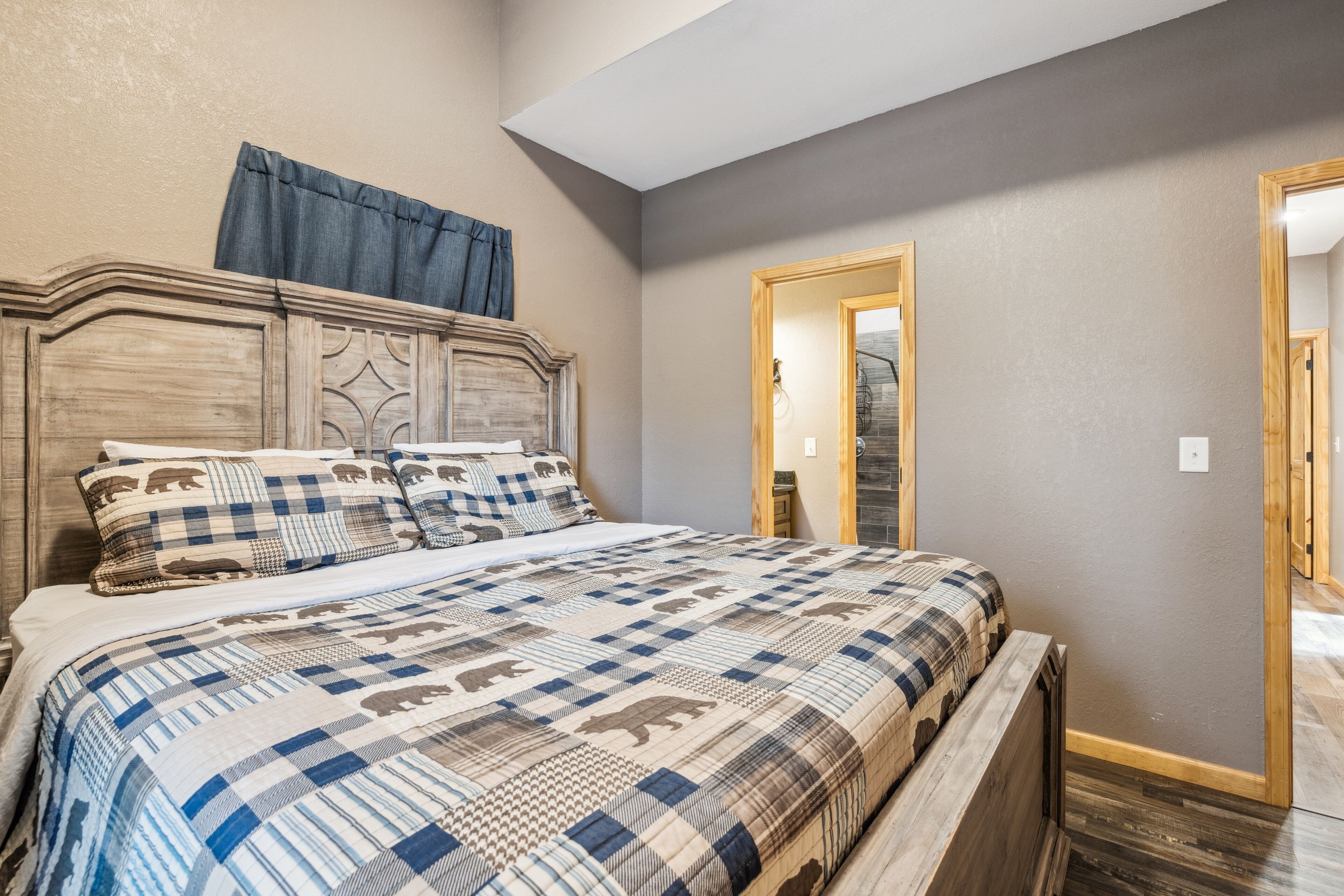 A bedroom with a large bed, a wooden headboard, and a mirror on the wall.