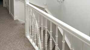 A staircase with white balusters and a light-colored carpet. - Flora's Palace (The Hague)