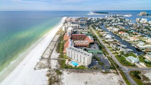 An aerial view of a coastal resort with beachfront hotels, a marina, and a beach.