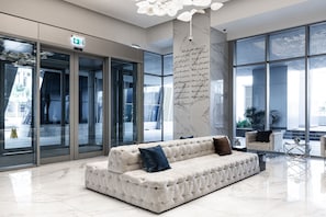 A modern lobby with a plush sofa, a marble floor, and large windows offering views of the outside.