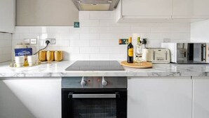 Una cocina moderna con armarios blancos, horno empotrado, microondas y una campana extractora de acero inoxidable.