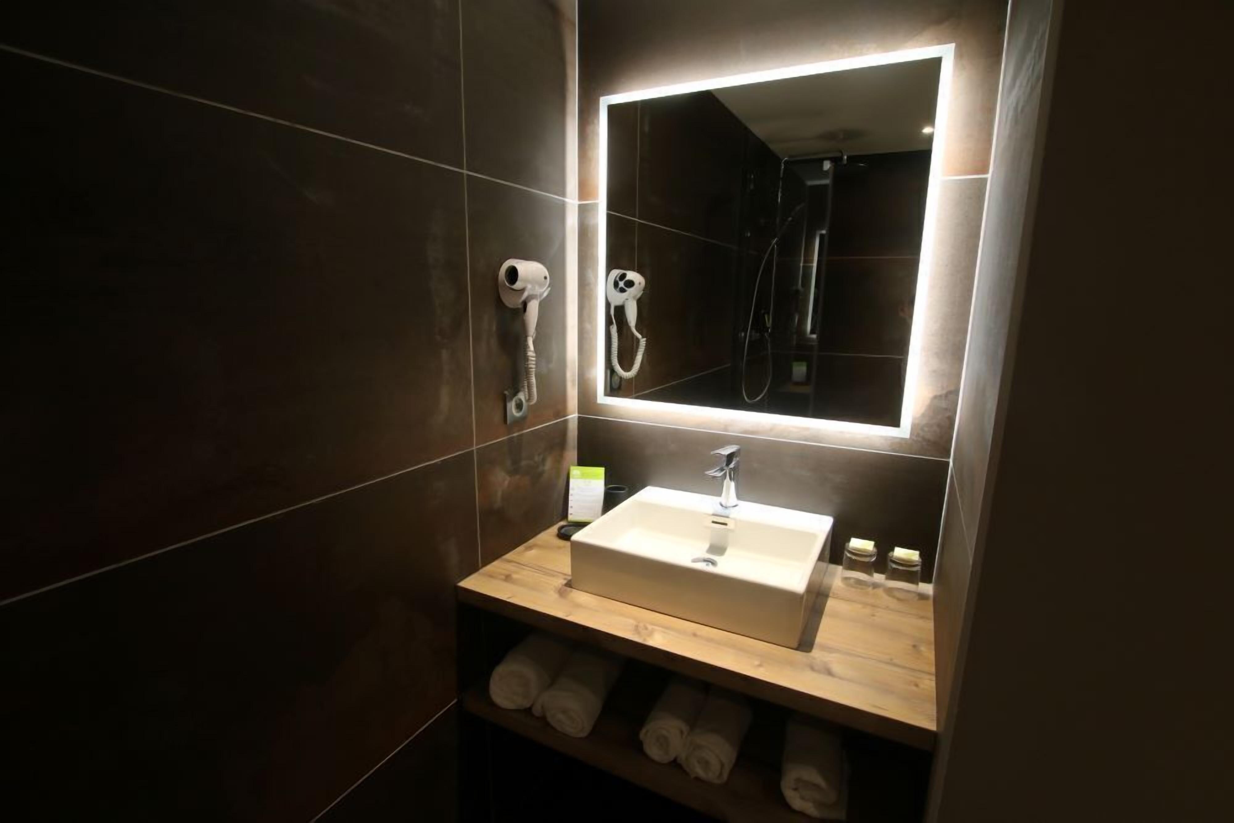 Une salle de bain moderne avec un grand miroir, un lavabo et un porte-serviettes.
