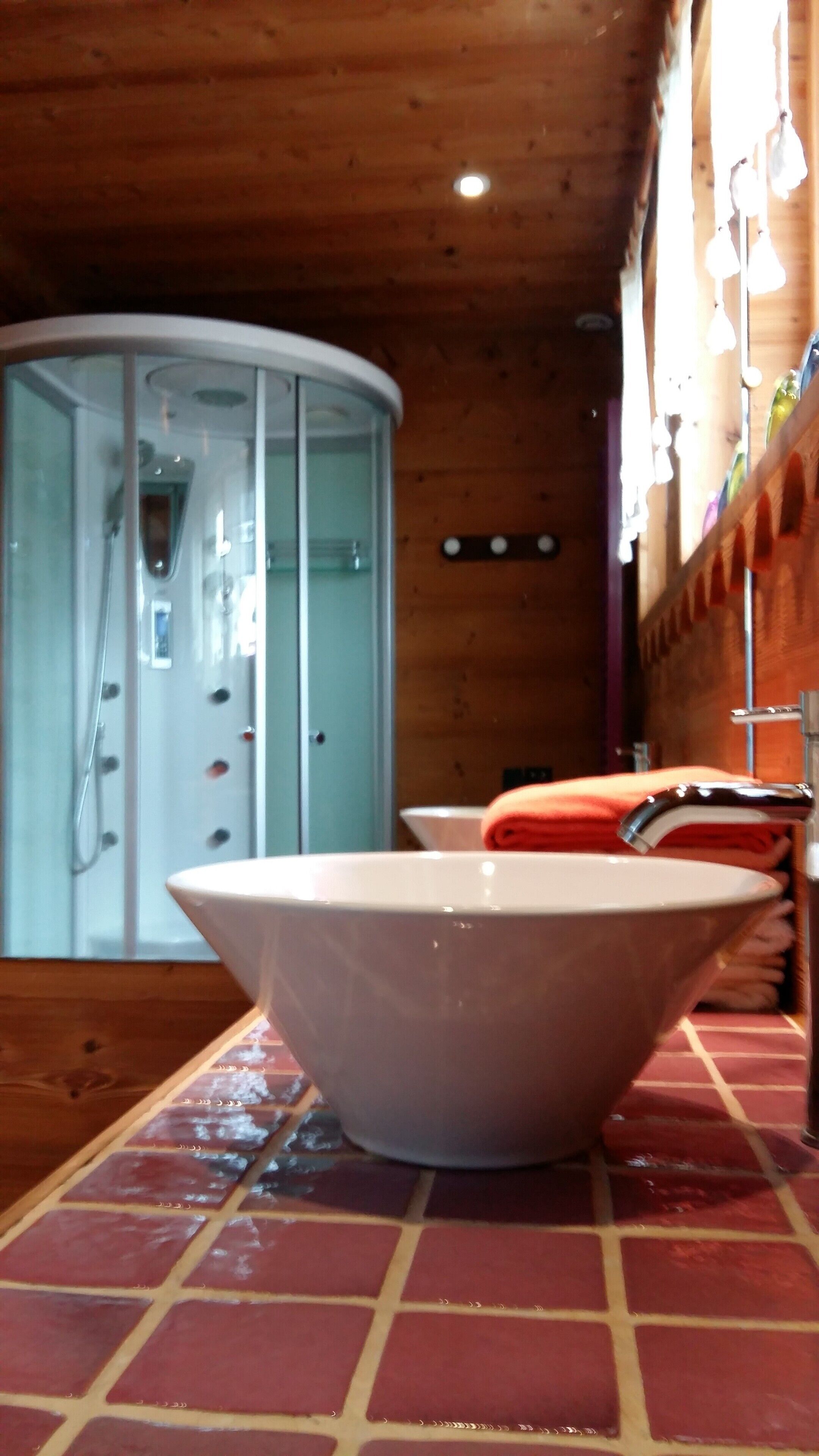 A bathroom with a large bathtub, a glass shower enclosure, and a wooden ceiling.