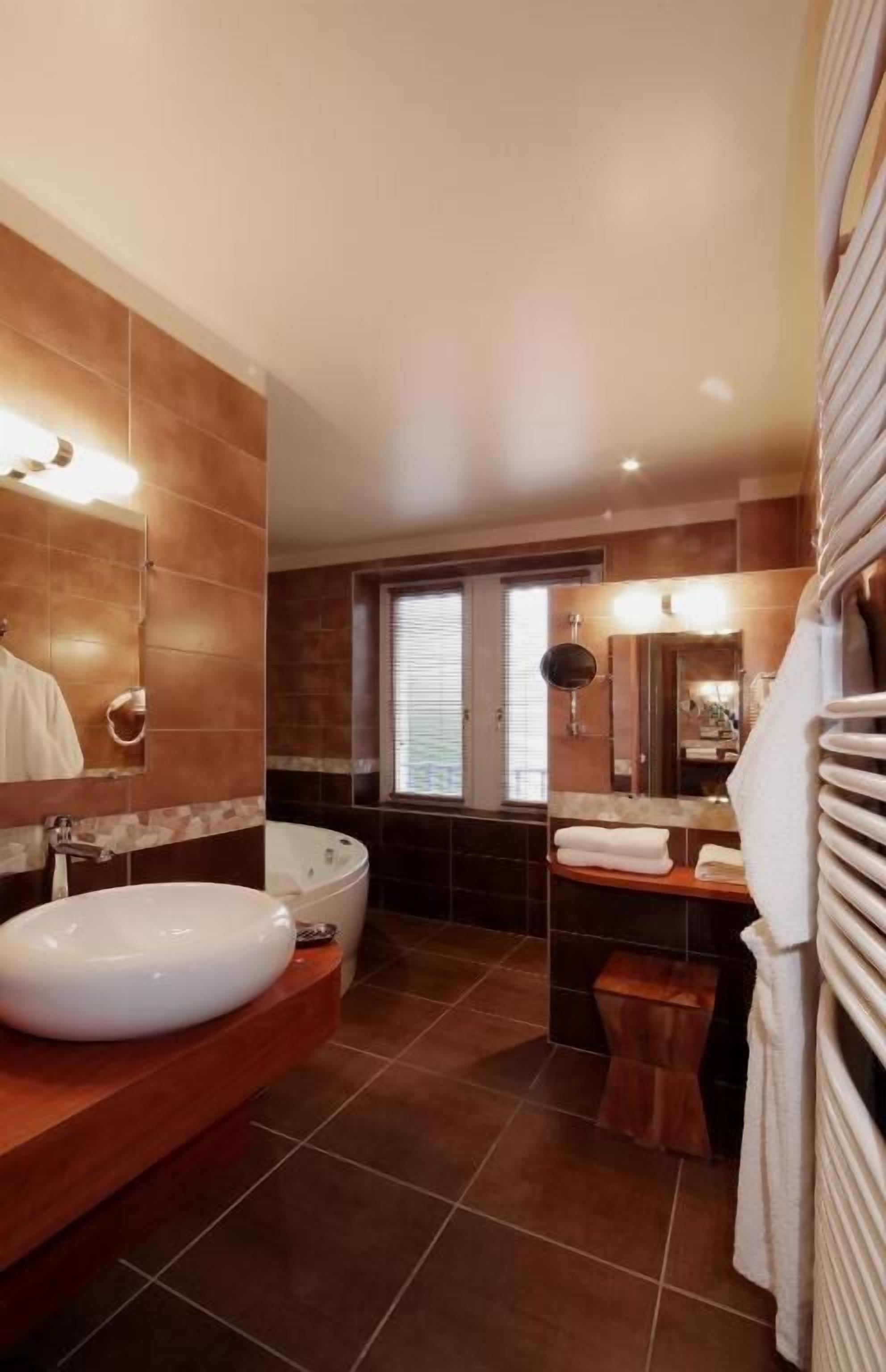 Un baño moderno con una bañera grande, un tocador con lavamanos y un espejo.