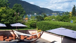 A poolside area with lounge chairs and umbrellas, overlooking a lake and forested hills. - hotel les loges du parc (Gérardmer)