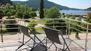 A balcony with two folding chairs, a view of a lake, and surrounding greenery. - hotel les loges du parc (Gérardmer)
