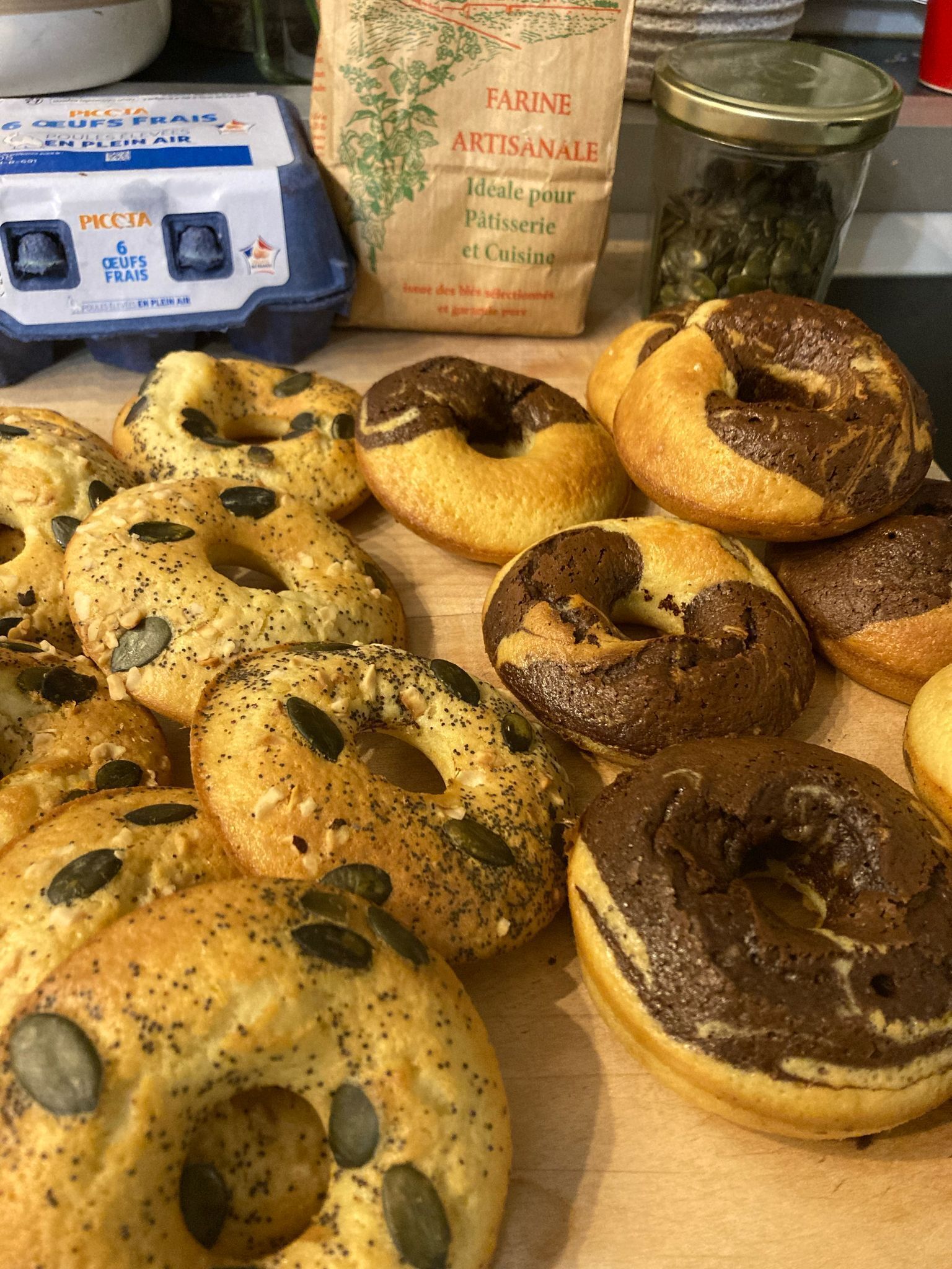 A variety of bagels with seeds on a wooden surface.