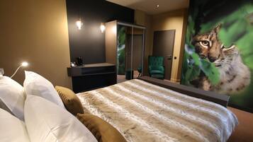 A modern bedroom with a large bed, a green armchair, a wardrobe, and a wall-mounted mirror.